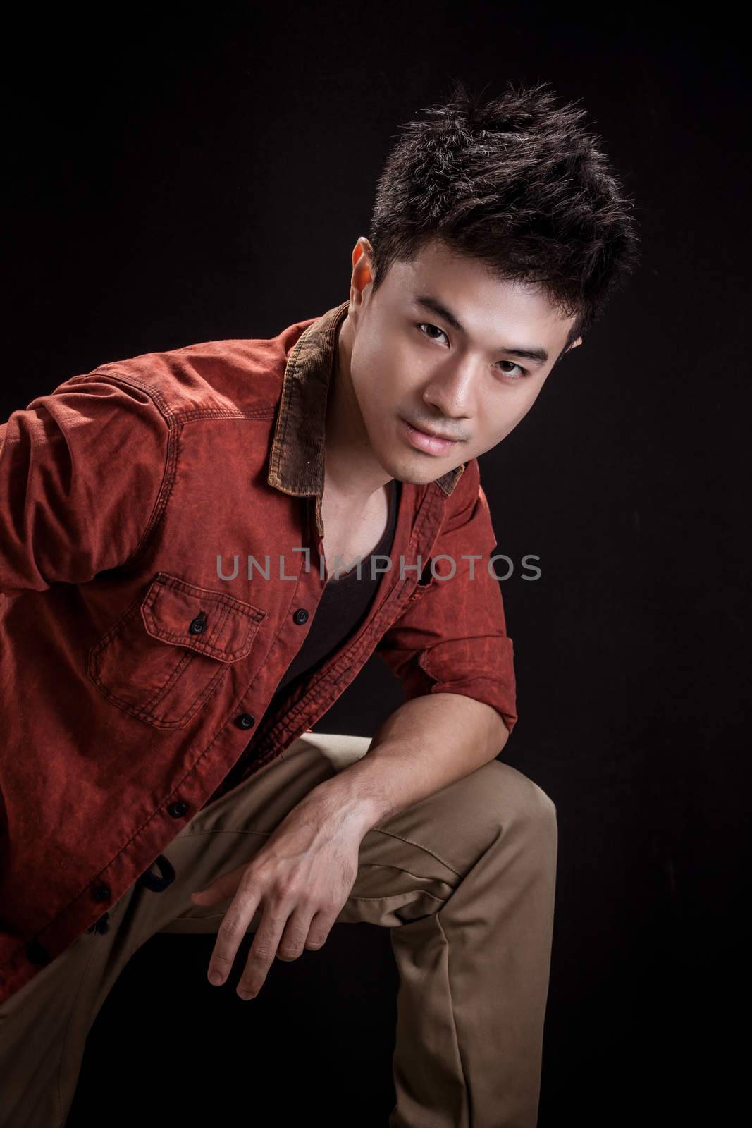 Portrait of Asian young man on black background - Casual red shirt and posing