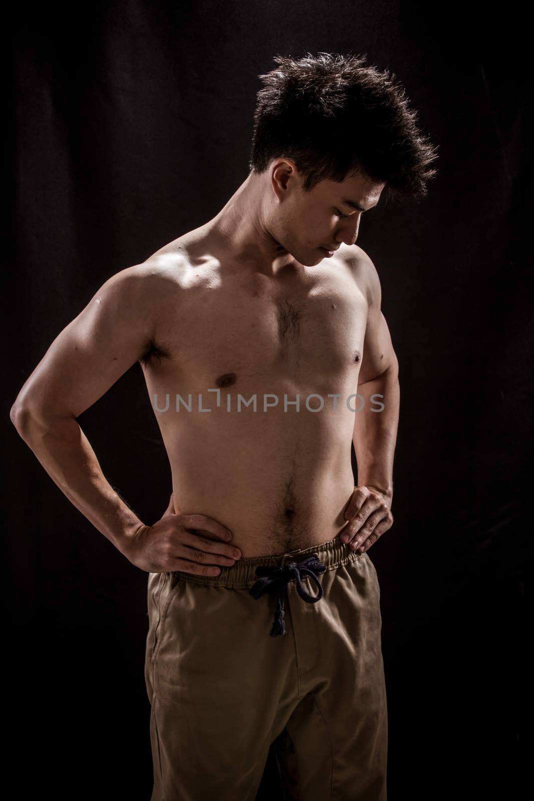 Topless portrait of Asian young man showing muscle and strengh