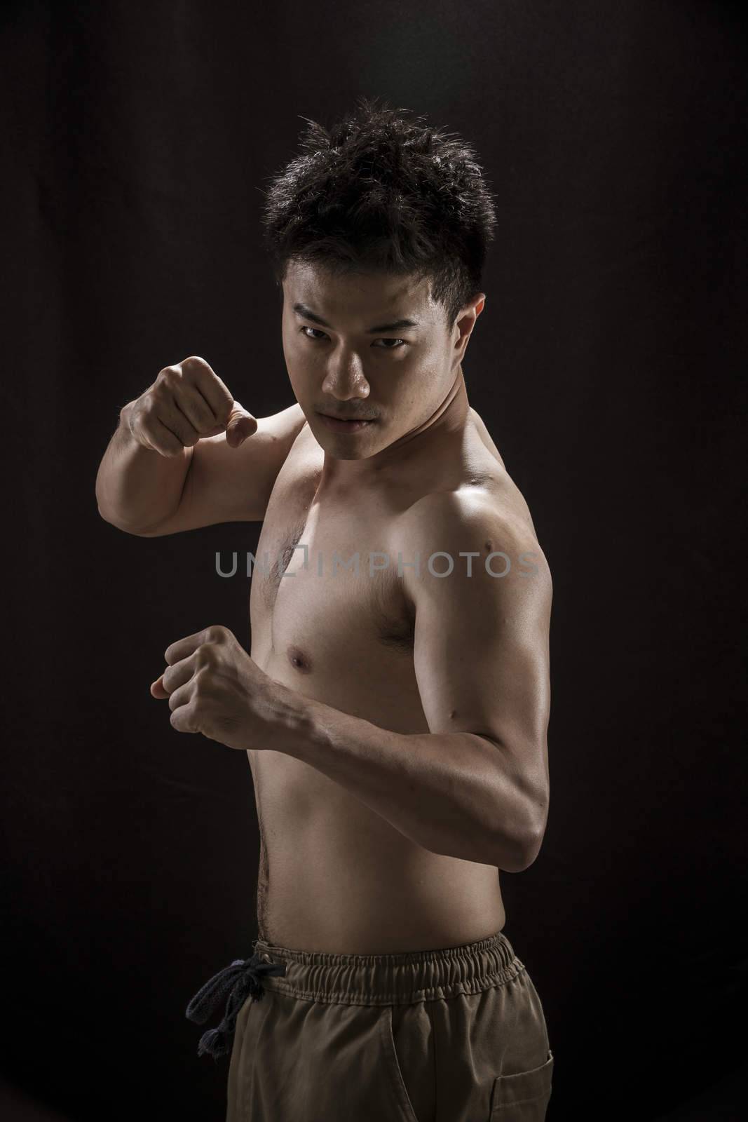Portrait of Asian young man on black background - fighter concpet, Muaythai, boxer