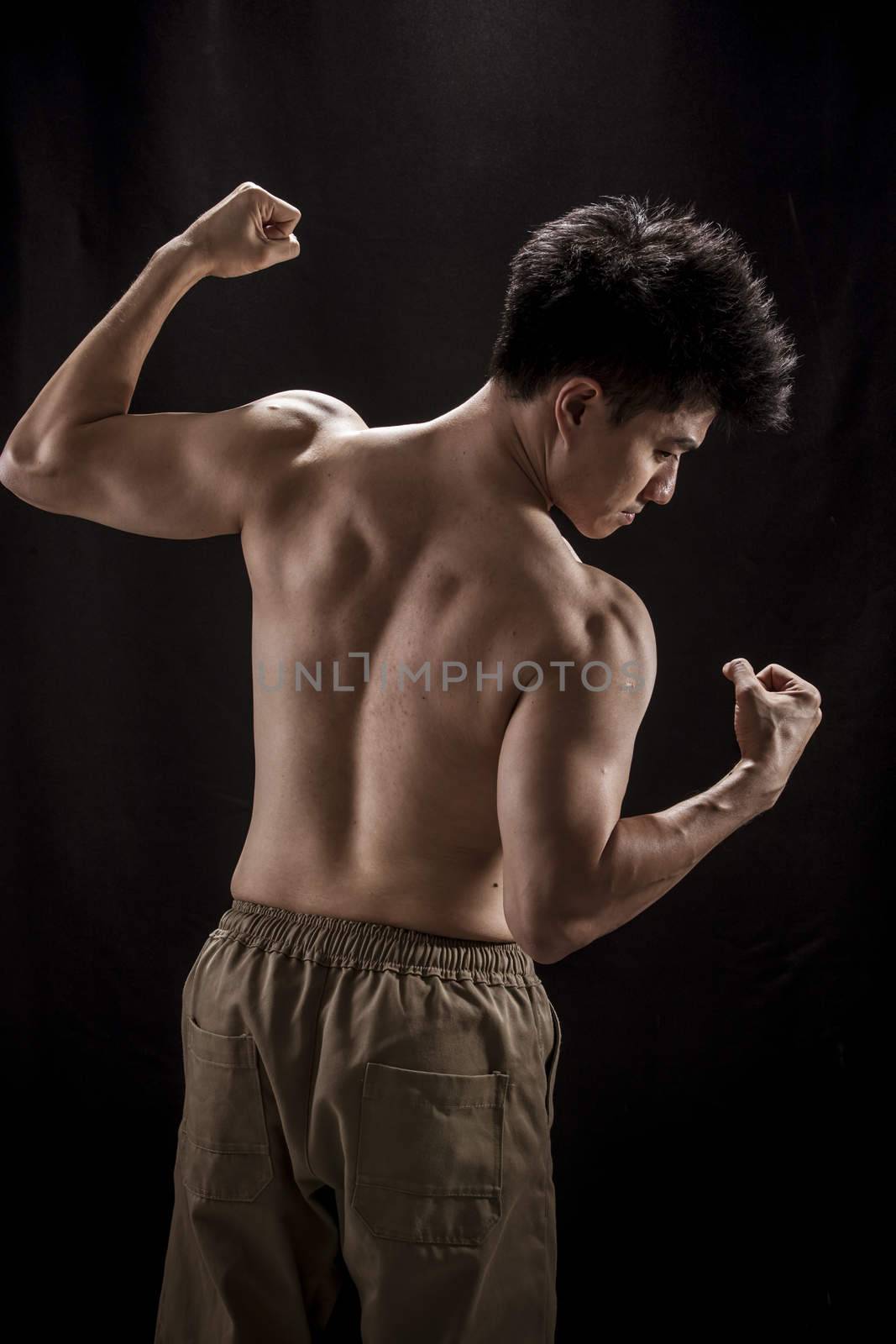 Topless portrait of Asian young man showing muscle and strengh