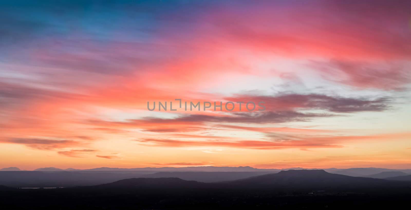 sunset scene with mountains in background, colorful sky with soft clouds