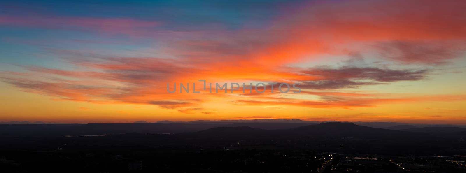 panoramic view of sunset scene with mountains in background, colorful sky with soft clouds