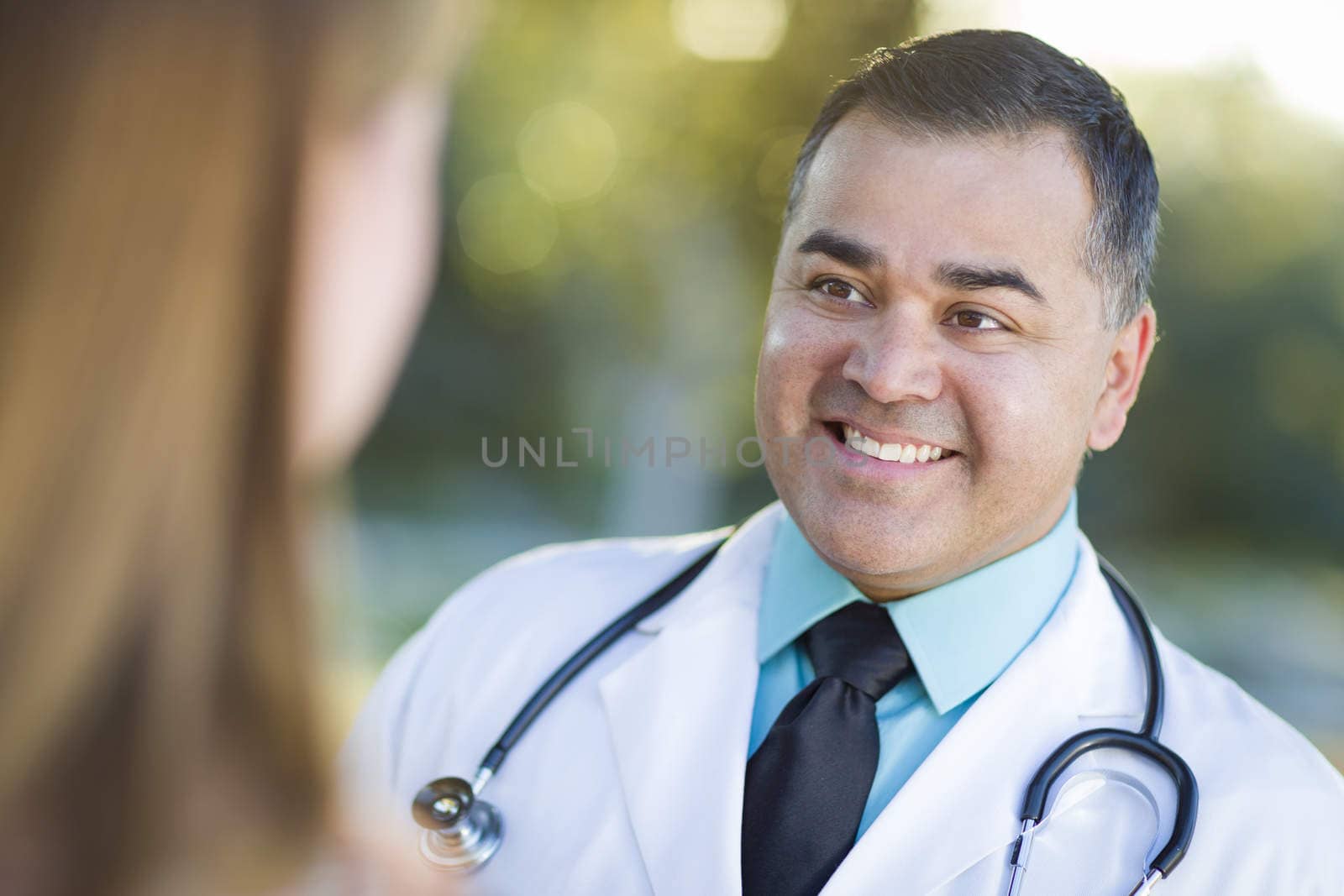 Hispanic Male Doctor or Nurse Talking With a Patient by Feverpitched