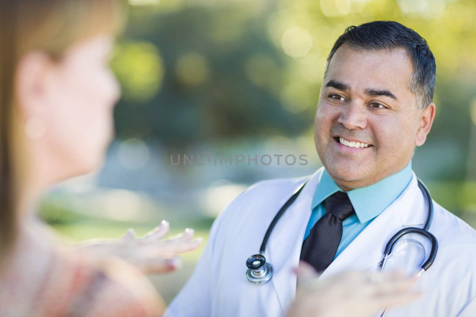 Hispanic Male Doctor or Nurse Talking With a Patient Outdoors.