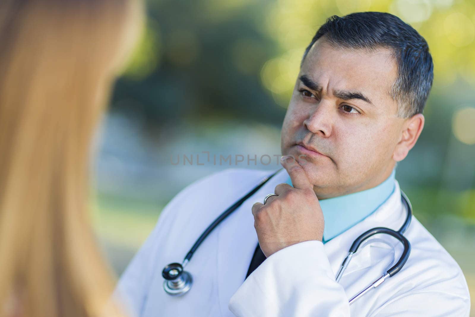 Hispanic Male Doctor or Nurse Talking With a Patient Outdoors.