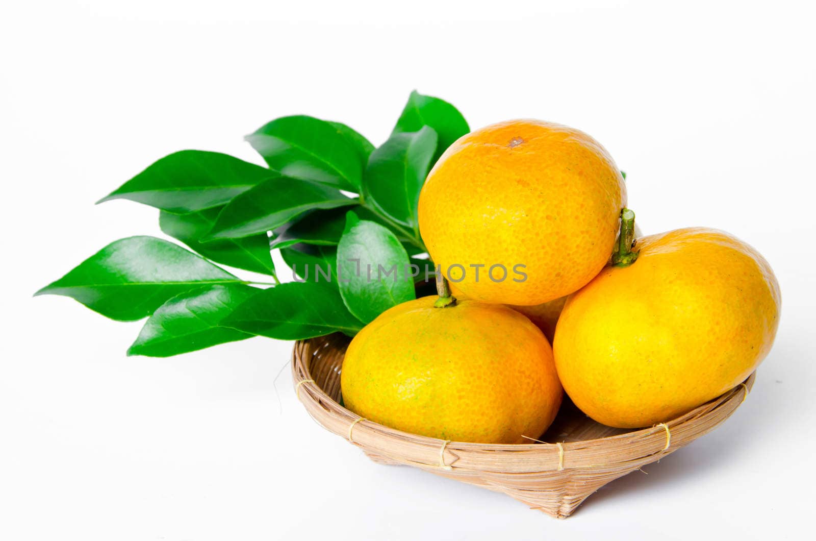 Many ripe orange fruit and leaves in weave basket.