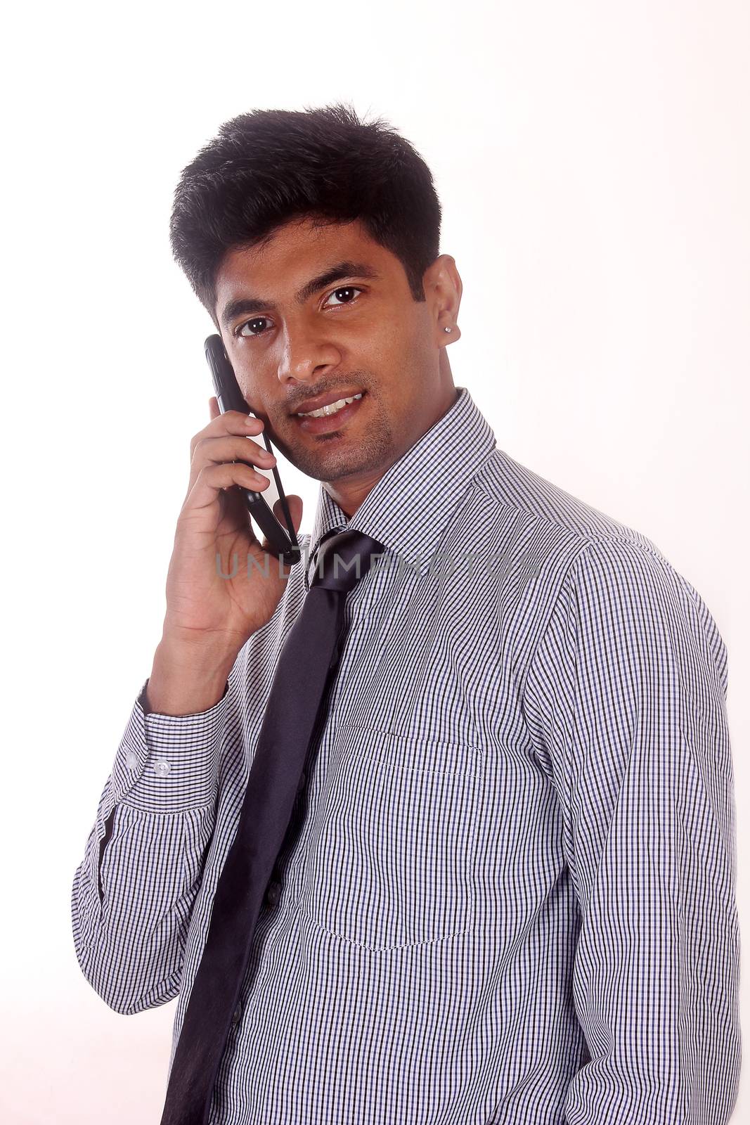 Portrait of businessman talking on mobile phone in office by ajithpride