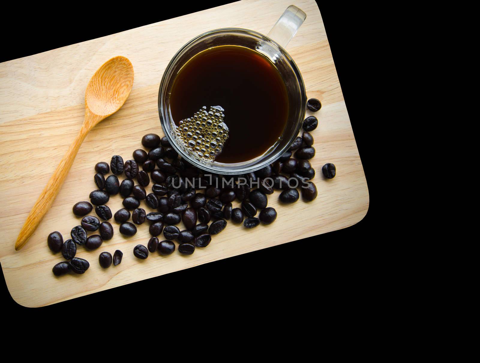 Black coffee in glass cup and seed coffee on wooden background.