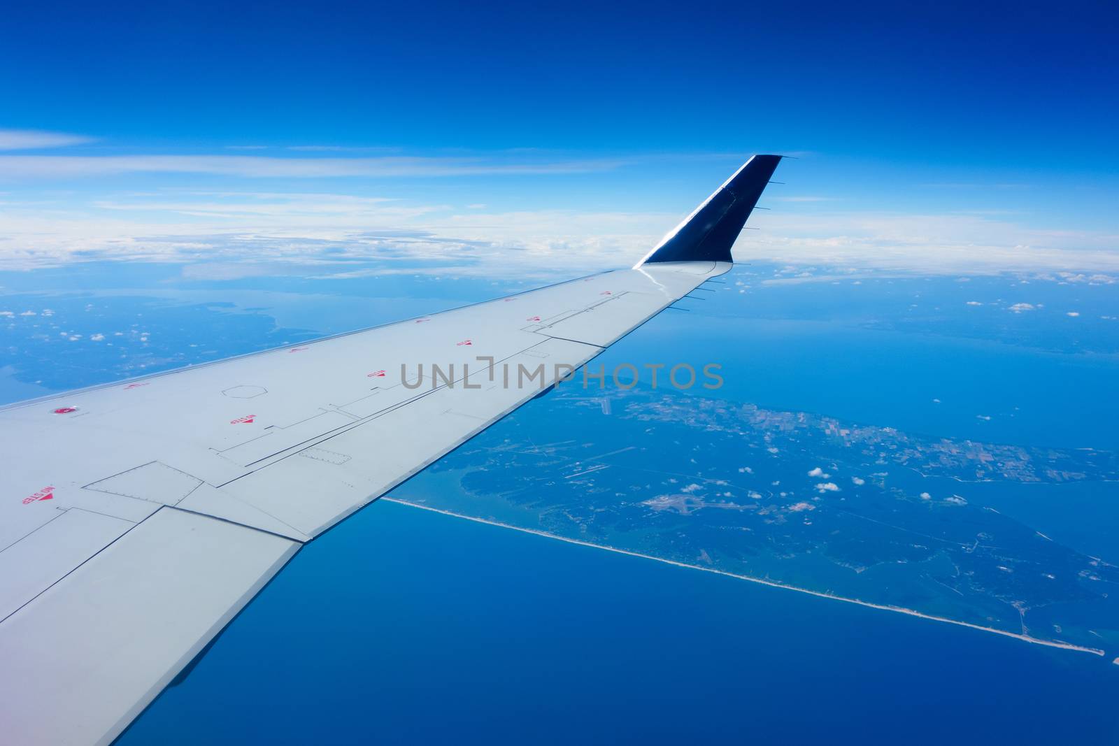 Wing of an airplane flying above a coastal region. 