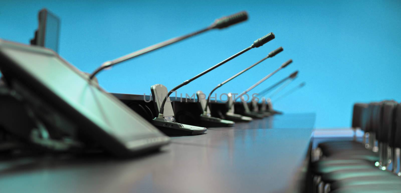 Conference table, microphones and office chairs, closeup, blue