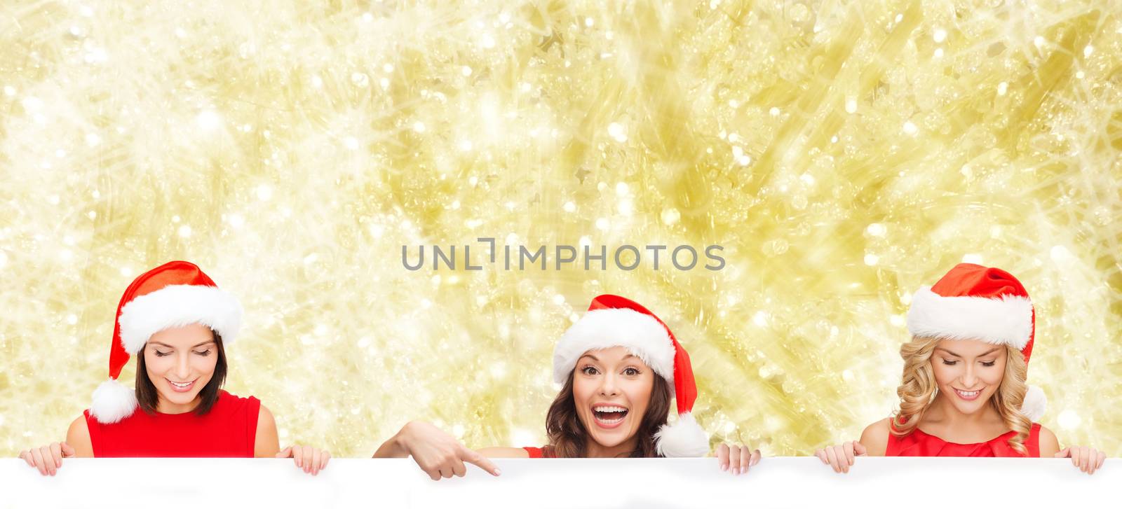 christmas, x-mas, people, advertisement and sale concept - happy women in santa helper hat with blank white board over yellow lights background