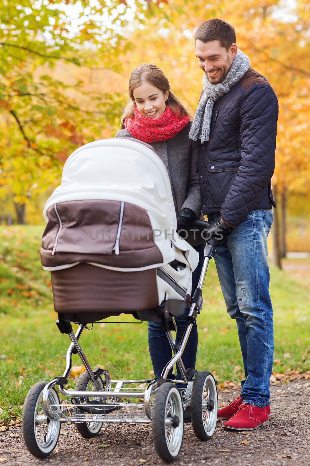 smiling couple with baby pram in autumn park by dolgachov