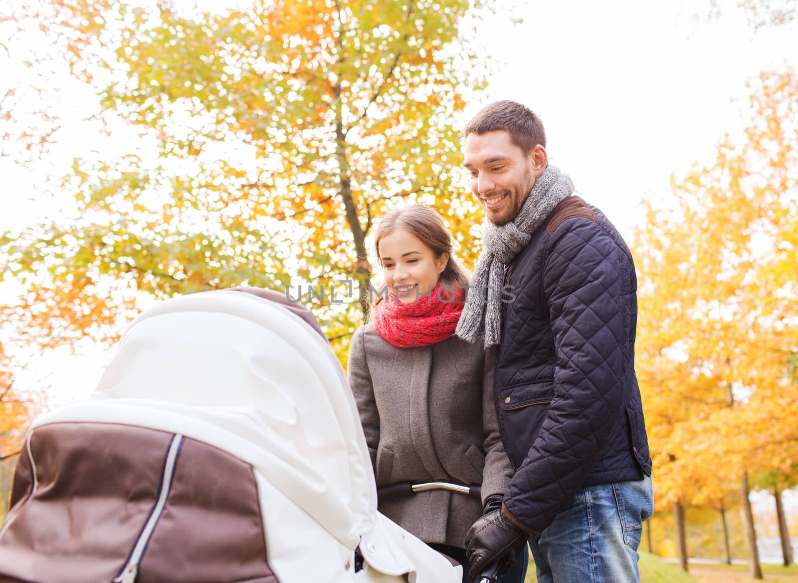 smiling couple with baby pram in autumn park by dolgachov