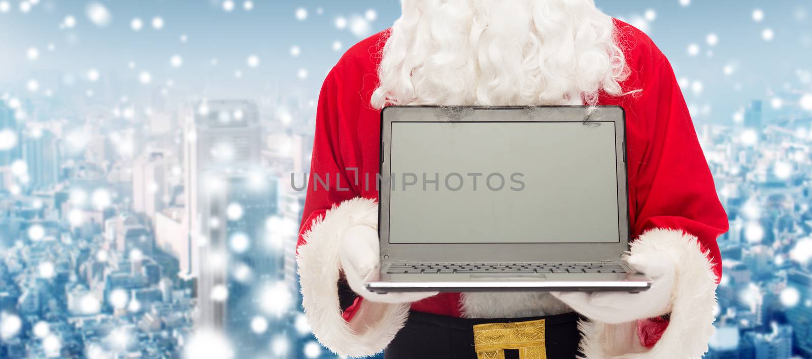 christmas, advertisement, technology, and people concept - close up of santa claus with laptop computer over snowy city background