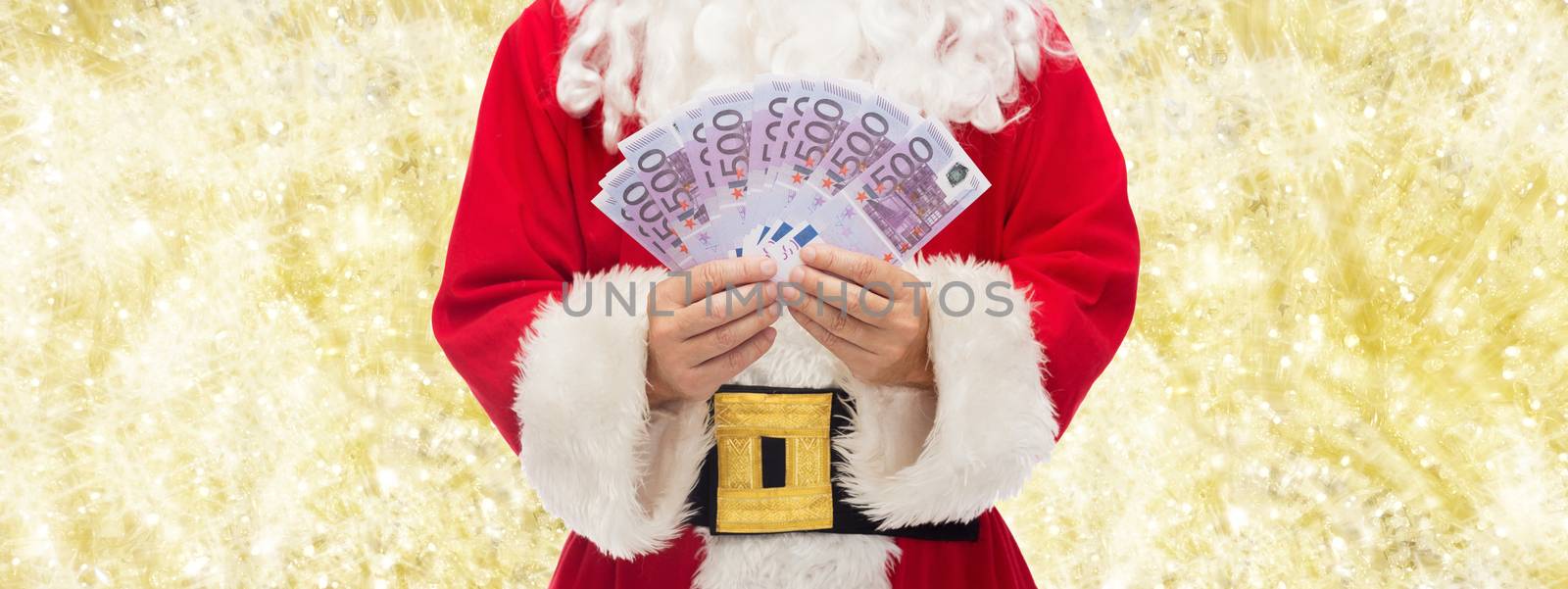 christmas, holidays, winning, currency and people concept - close up of santa claus with euro money over yellow lights background