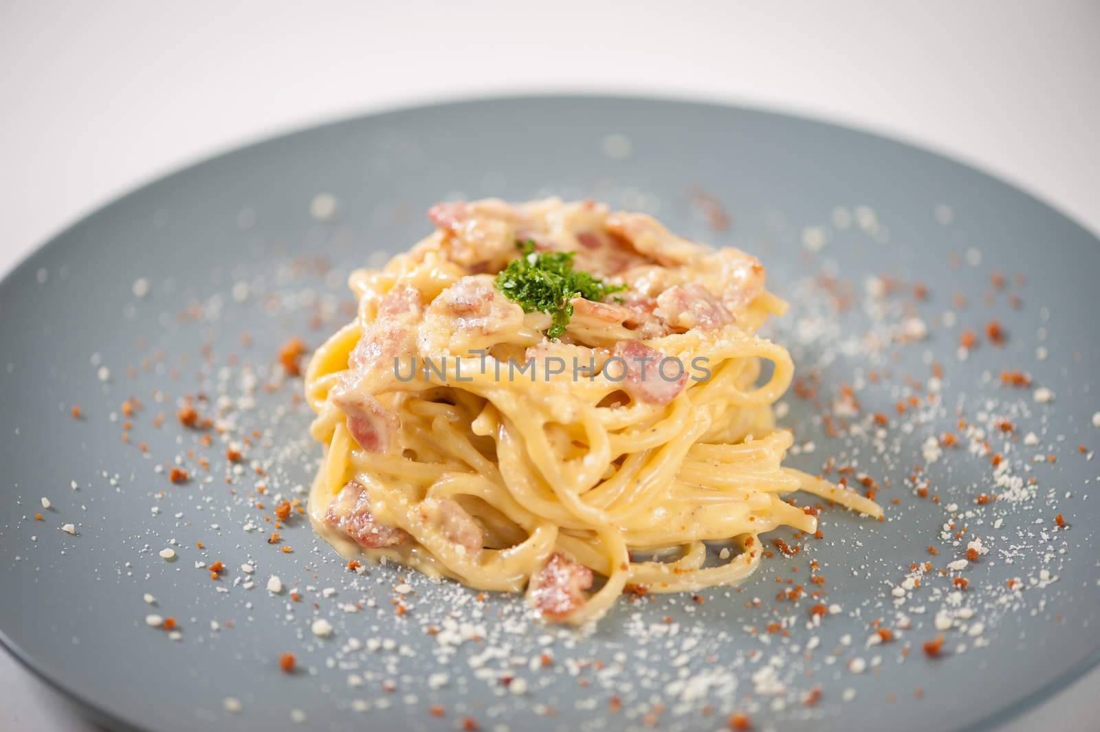 Carbonara pasta with bacon in grey ceramic dish.