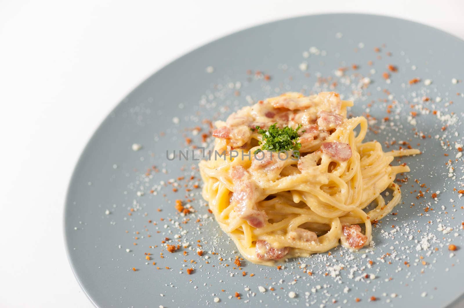 Carbonara pasta with bacon in grey ceramic dish.