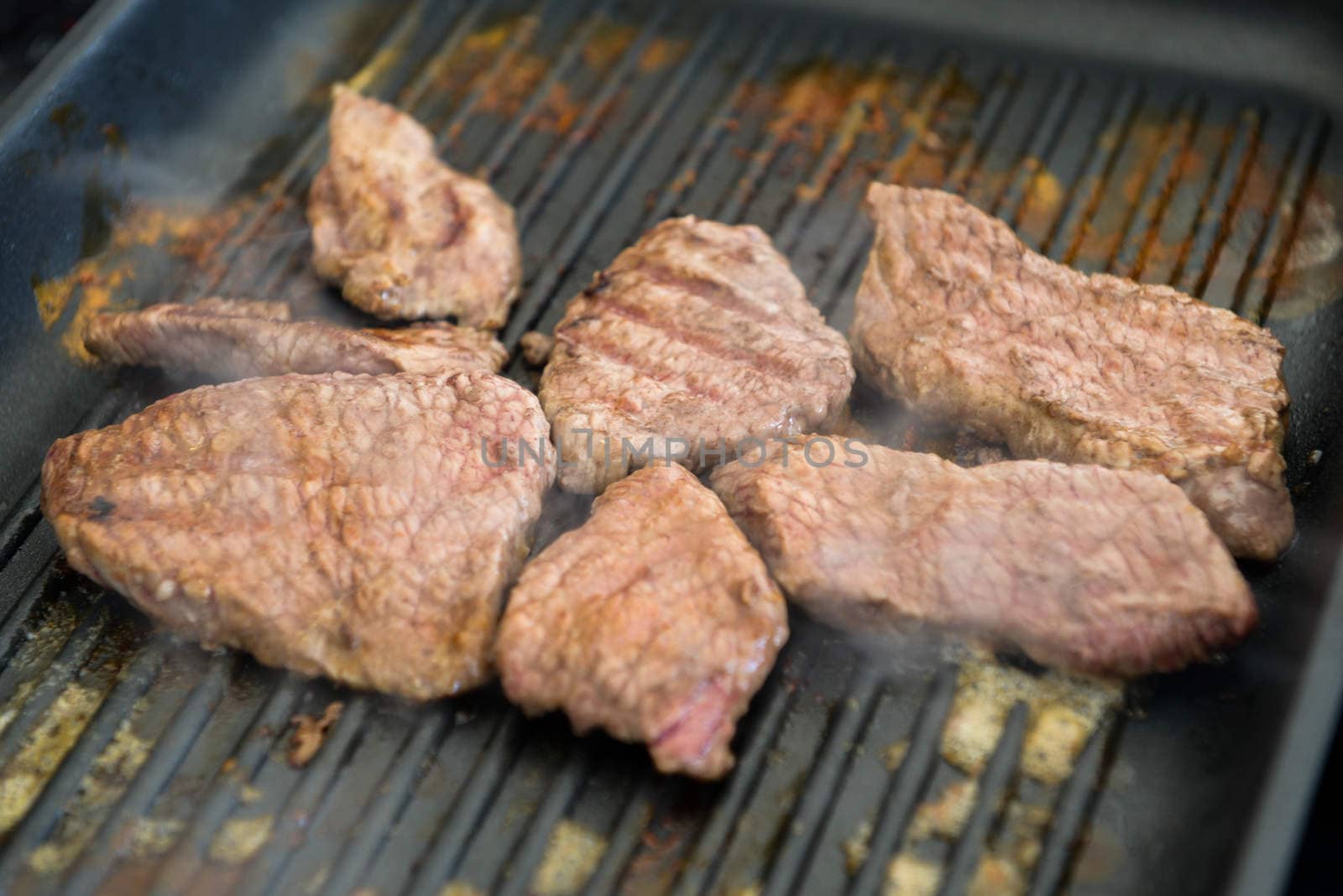 cooking steaks on a hot grill in a summer day