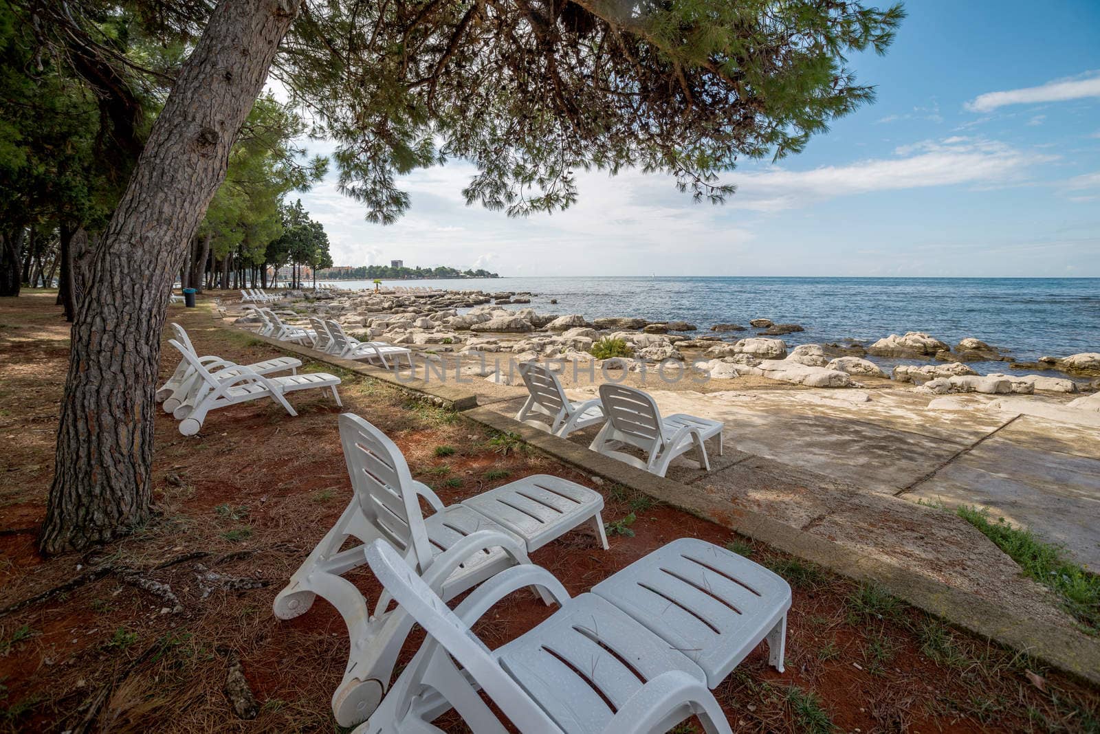 loungers on the rocky beach by vlaru