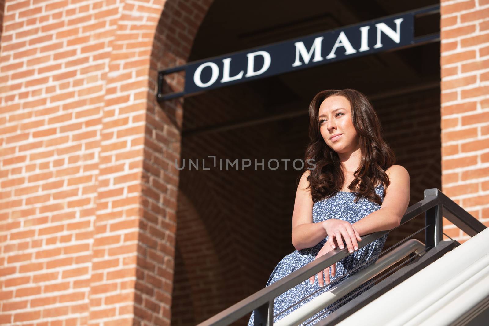 Thinking single female standing outdoors beneath sign