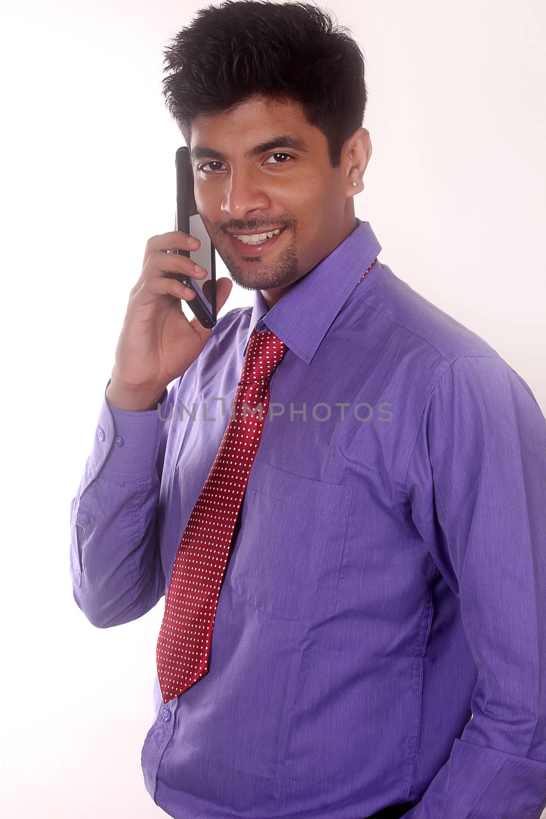 Portrait of businessman talking on mobile phone in office by ajithpride