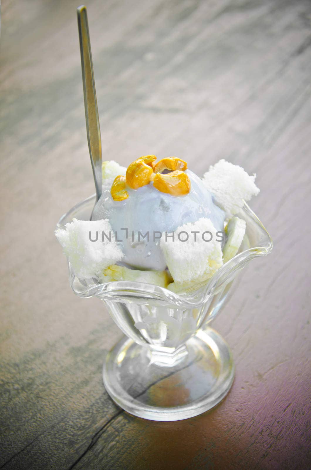 Taro ice cream with cashew in glass cup on wood table.