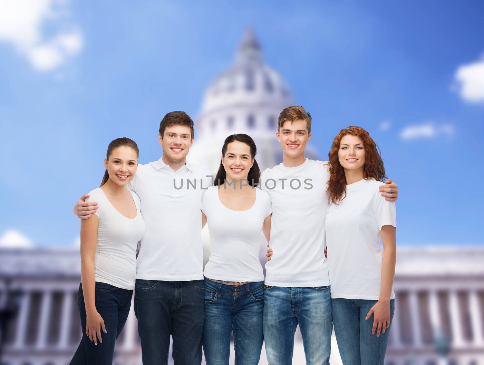 advertising, friendship, tourism and people concept - group of smiling teenagers in white blank t-shirts over white house background