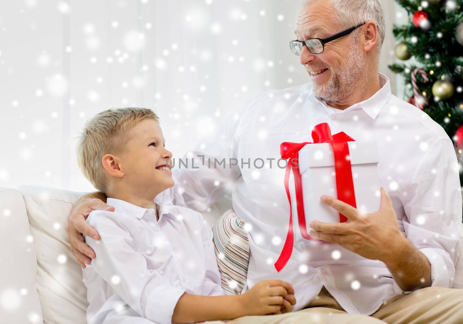 smiling grandfather and grandson with gift box by dolgachov
