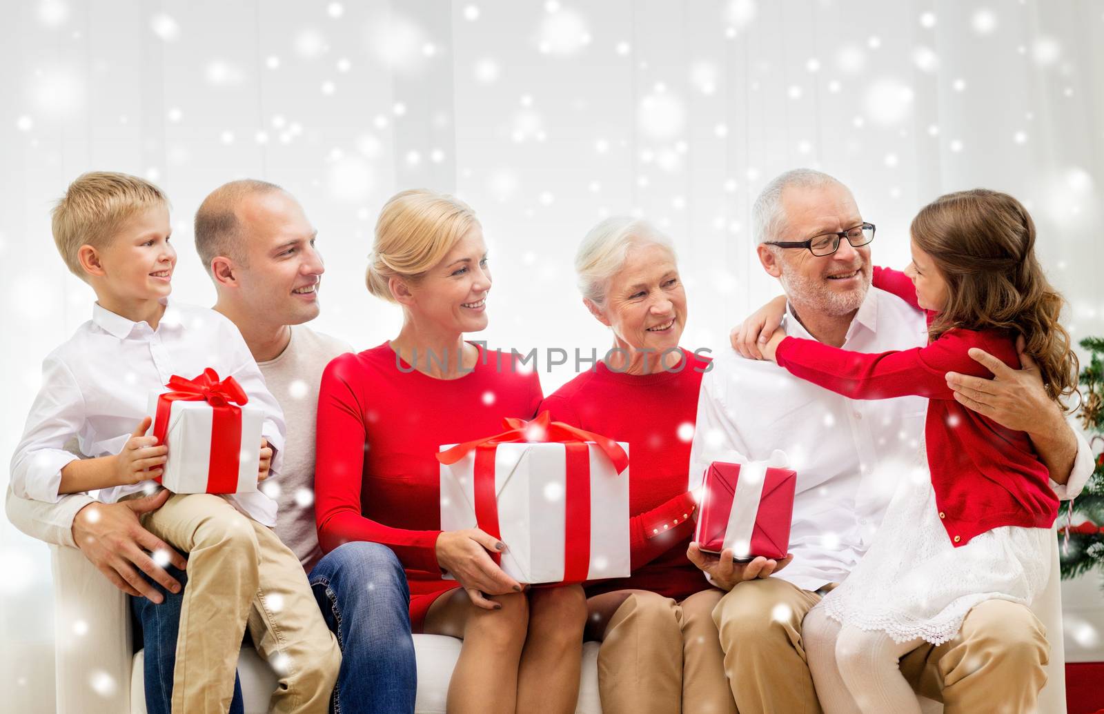 family, holidays, generation, christmas and people concept - smiling family with gift boxes sitting on couch at home