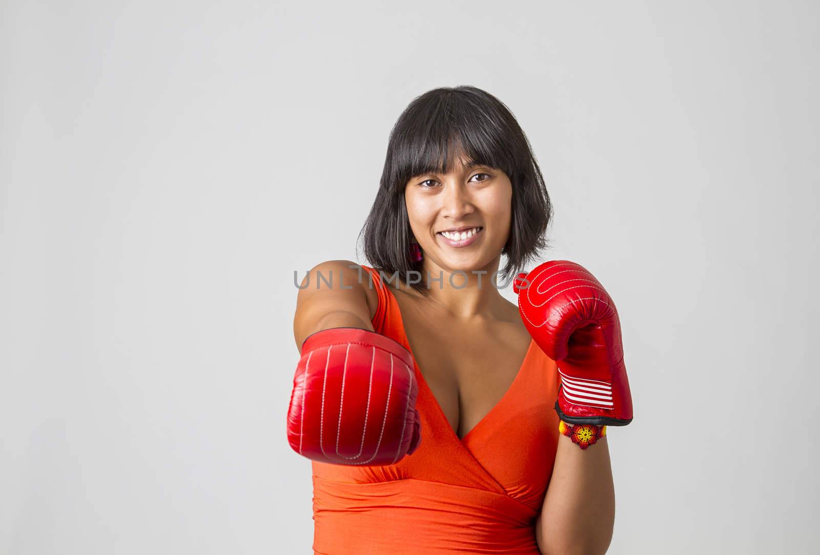 twenty something asian woman wearing a low cut orange dress with great smile throwing a right jab