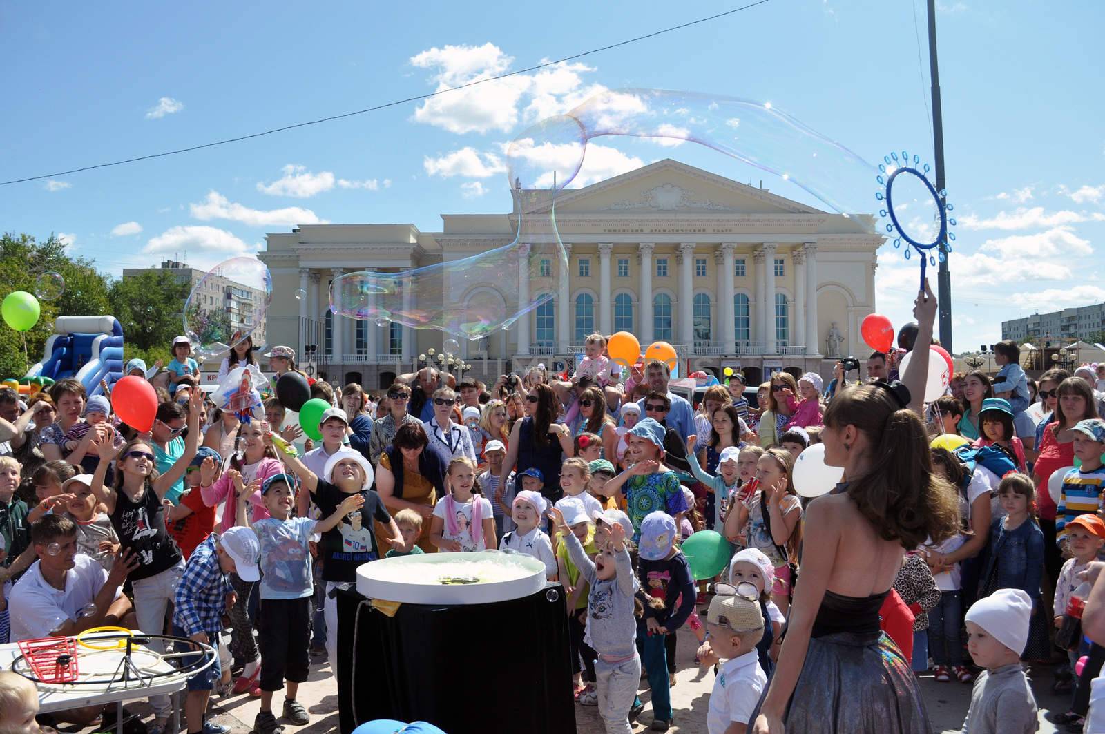 Happy children catch soap bubbles on the street in the city of Tyumen, Russia.