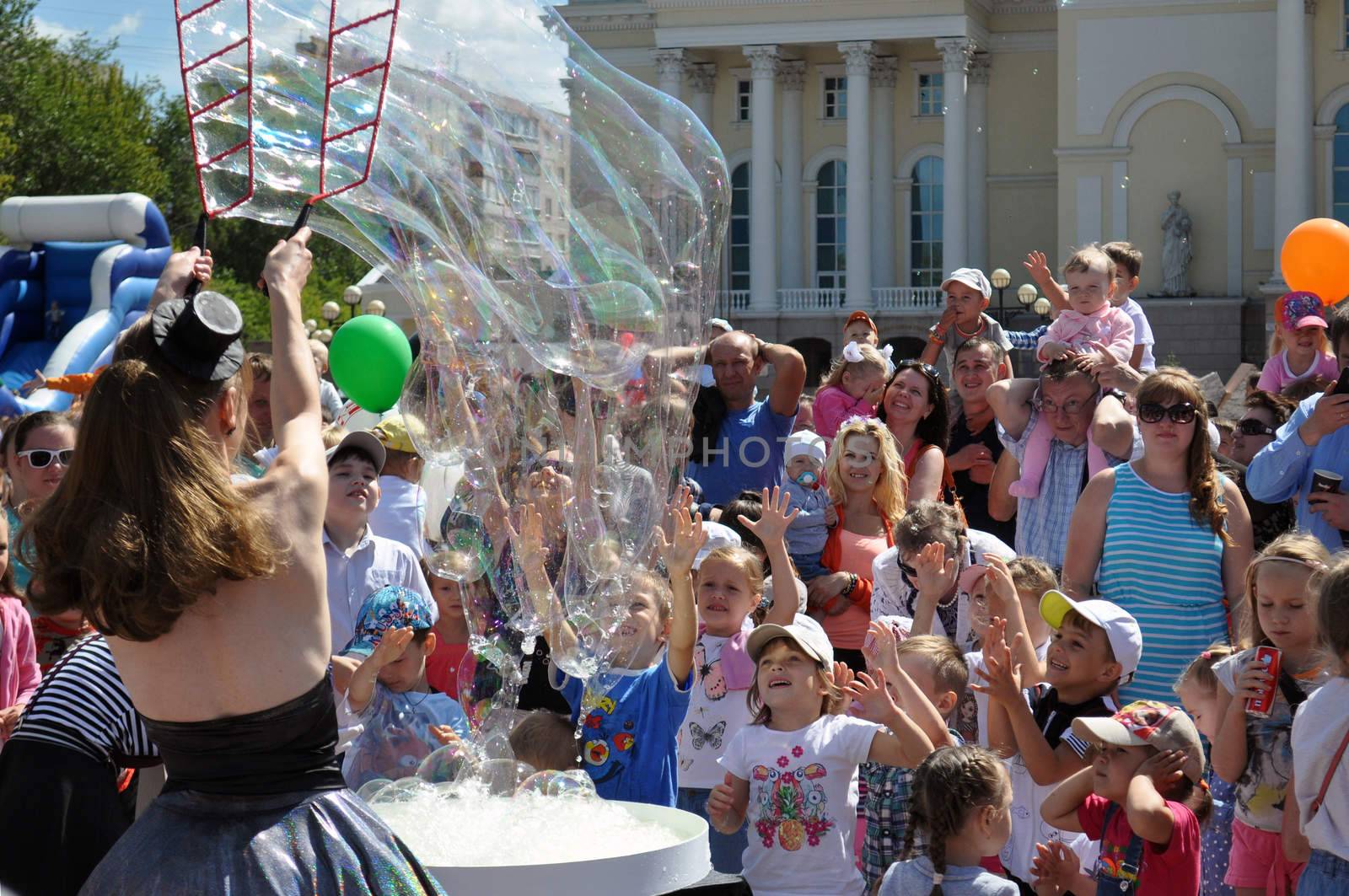 Happy children catch soap bubbles on the street.