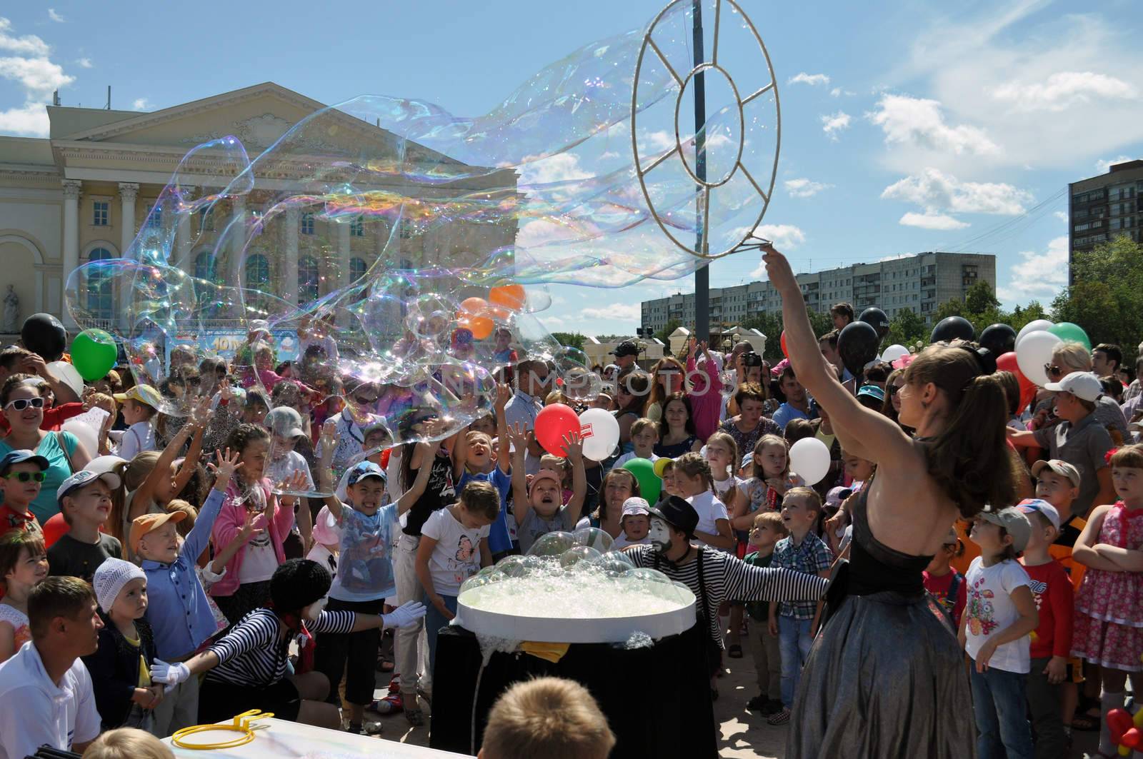 Happy children catch soap bubbles on the street in the city of Tyumen, Russia.