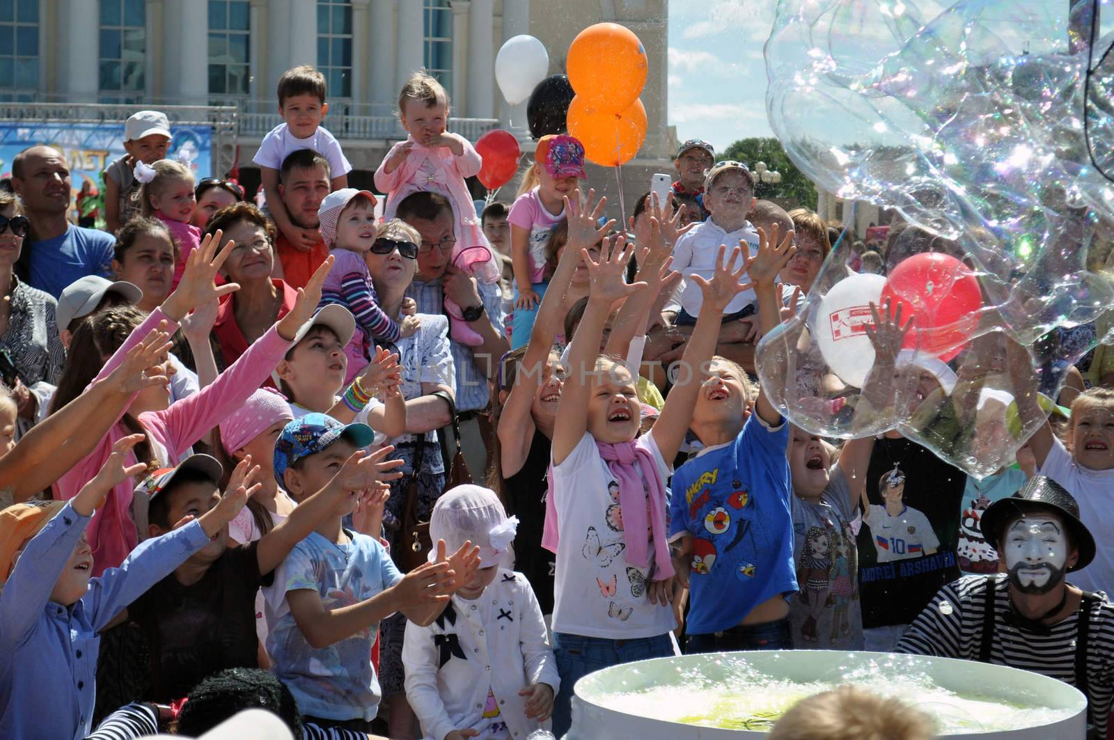 Happy children catch soap bubbles on the street in the city of Tyumen, Russia.