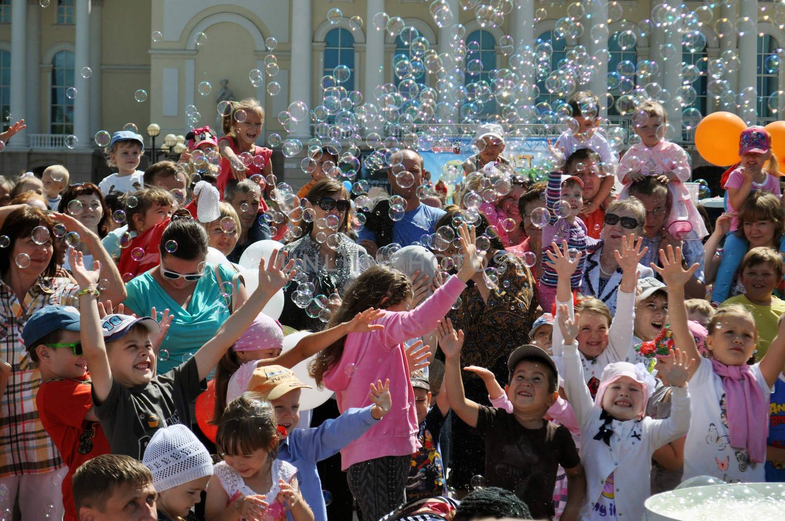 Happy children catch soap bubbles on the street in the city of T by veronka72