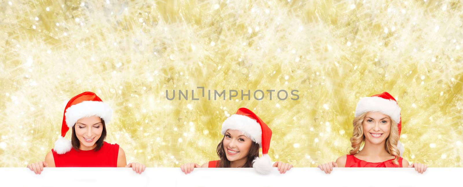 christmas, x-mas, people, advertisement and sale concept - happy women in santa helper hat with blank white board over yellow lights background