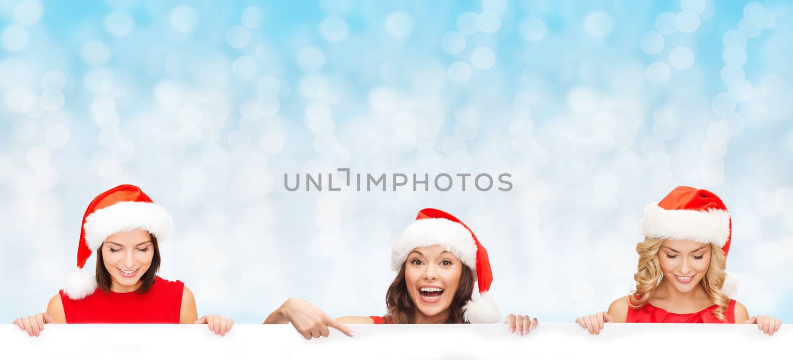 christmas, x-mas, people, advertisement and sale concept - happy women in santa helper hat with blank white board over blue lights background