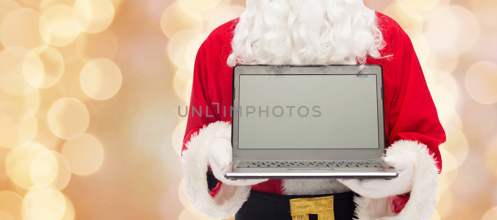 christmas, advertisement, technology, and people concept - close up of santa claus with laptop computer over beige lights background