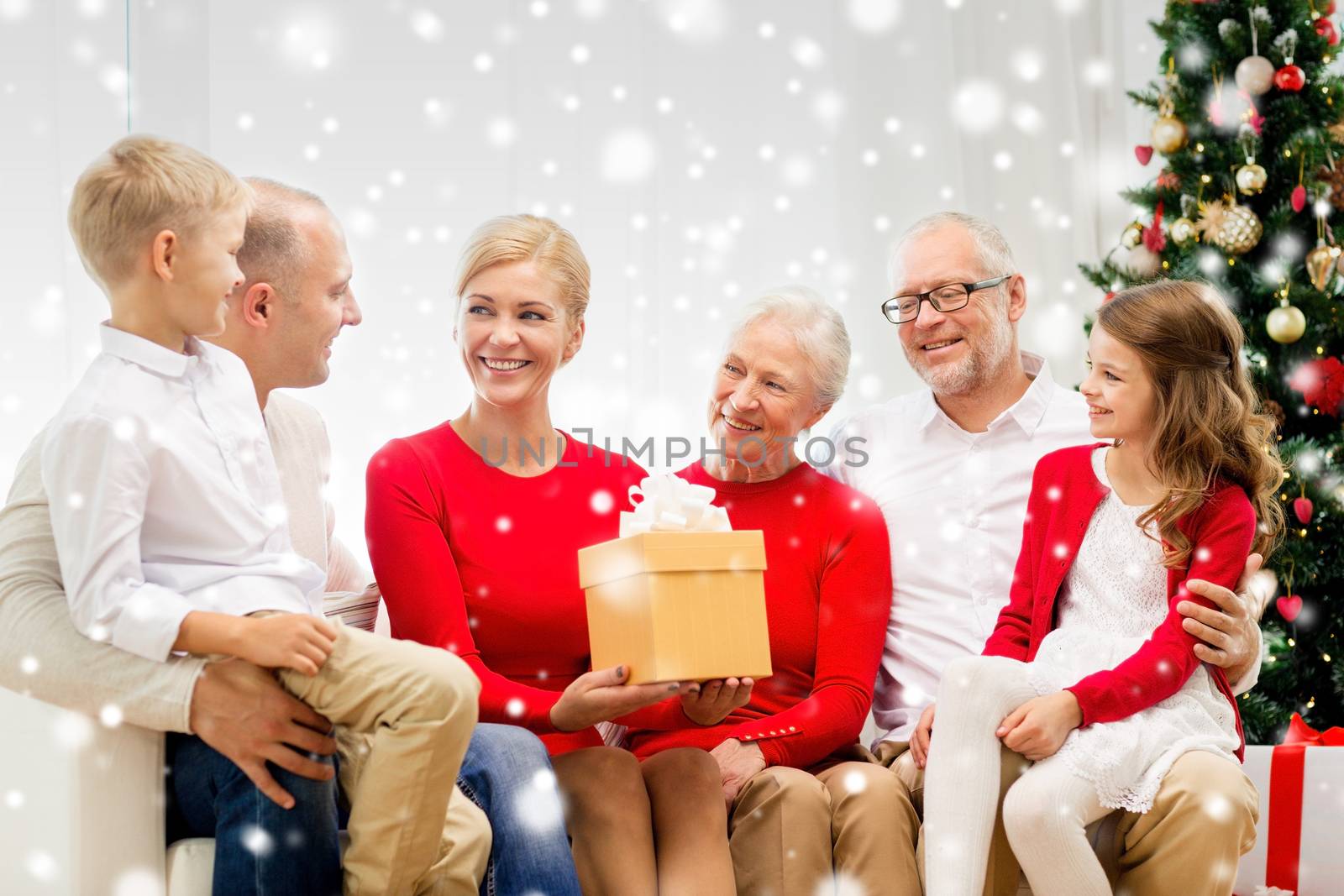 family, holidays, generation, christmas and people concept - smiling family with gift box sitting on couch at home