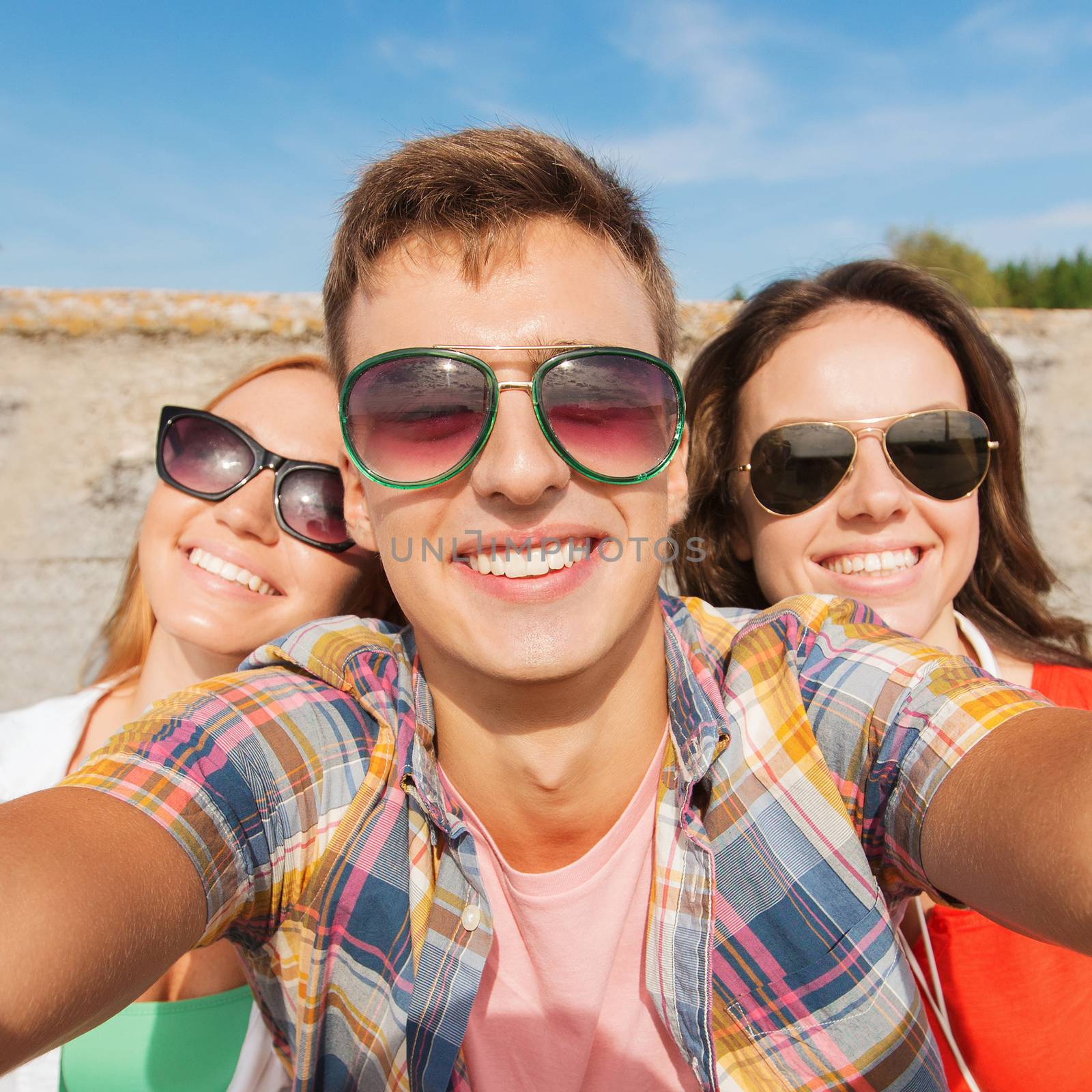friendship, leisure, summer, technology and people concept - group of smiling friends taking selfie outdoors