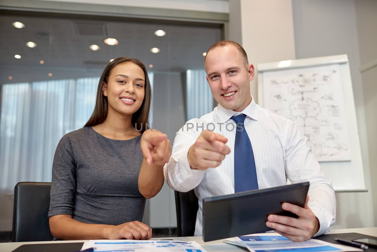 smiling businesspeople with tablet pc in office by dolgachov