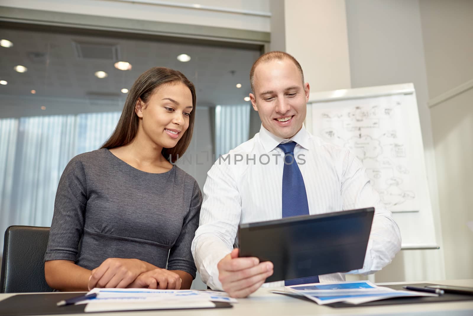 smiling businesspeople with tablet pc in office by dolgachov