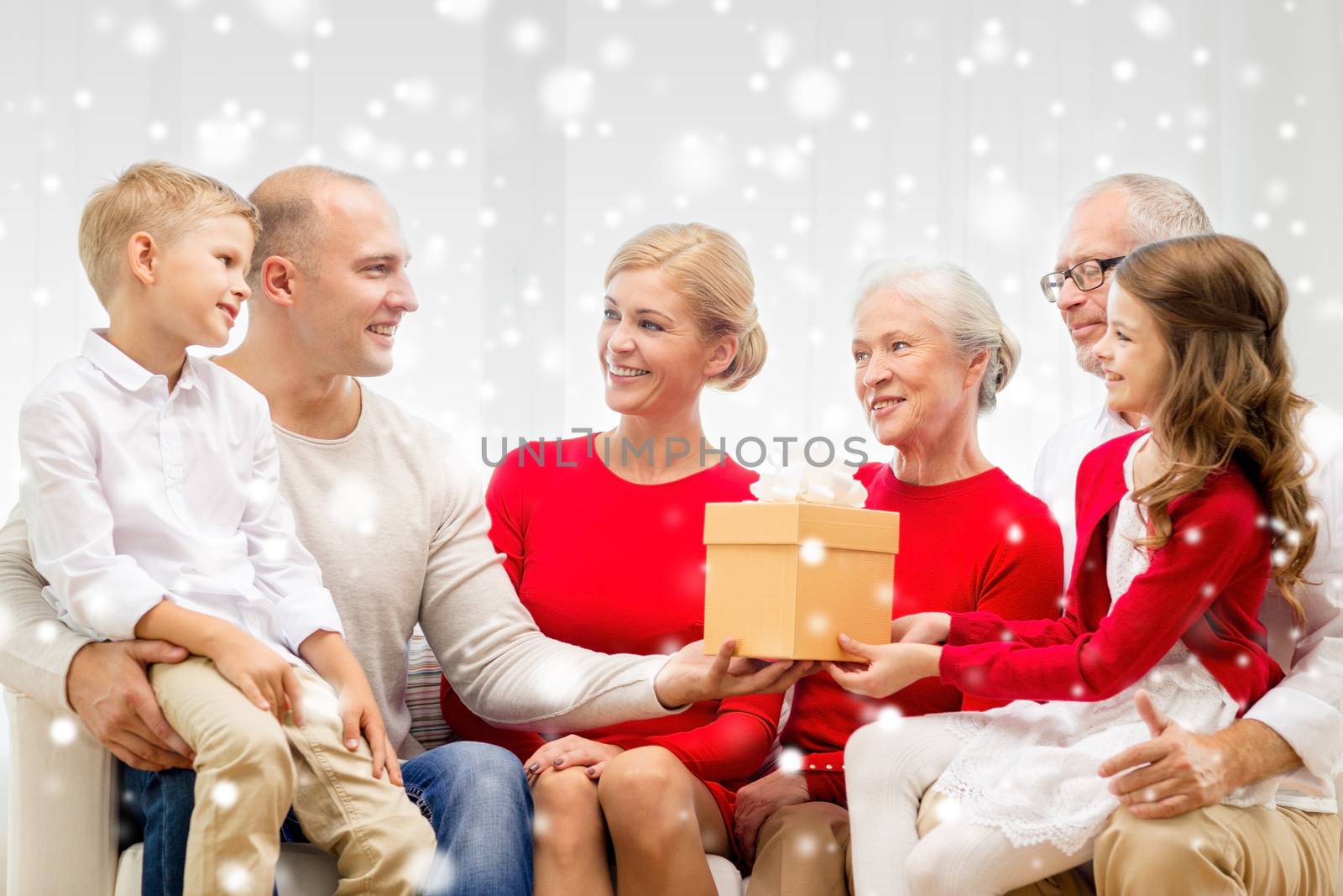 family, holidays, generation, christmas and people concept - smiling family with gift box sitting on couch at home