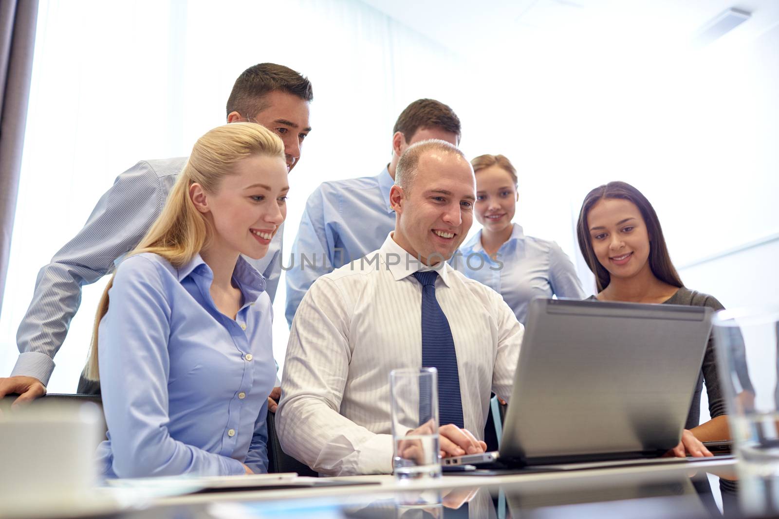 smiling business people with laptop in office by dolgachov