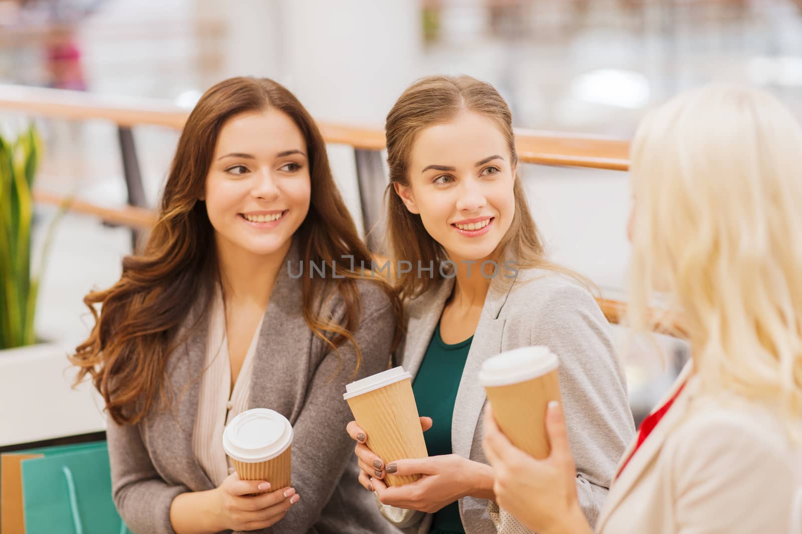 young women with shopping bags and coffee in mall by dolgachov