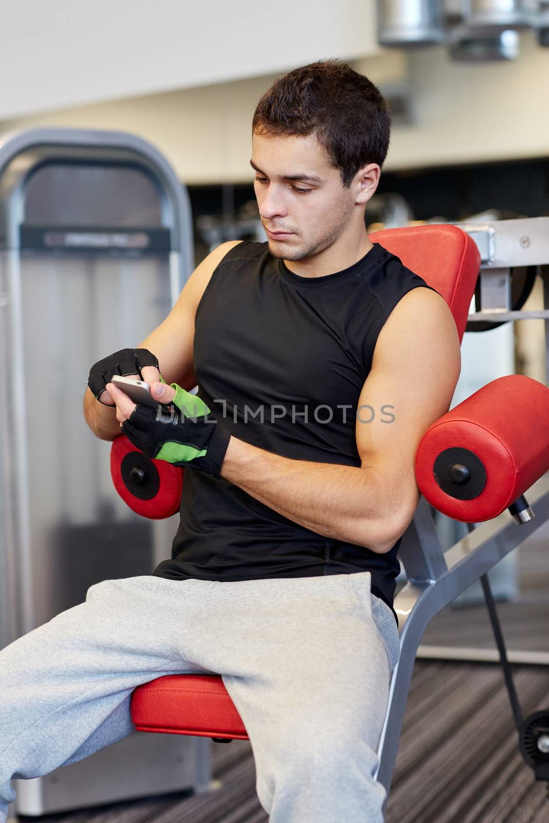 young man with smartphone in gym by dolgachov