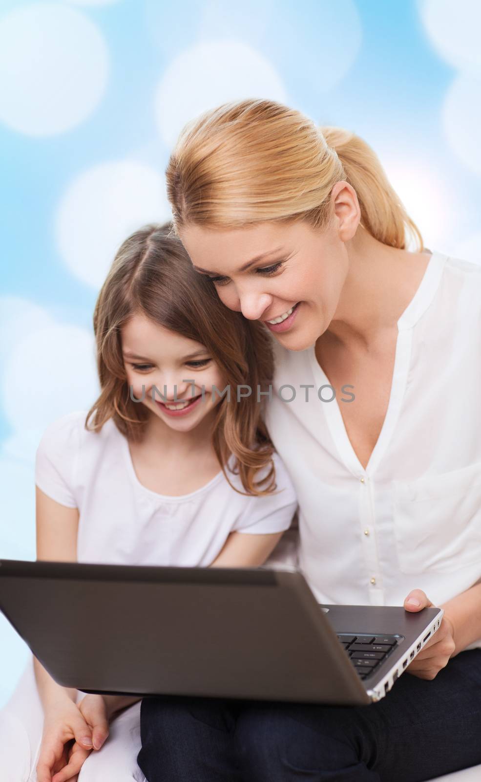 smiling mother and little girl with laptop by dolgachov