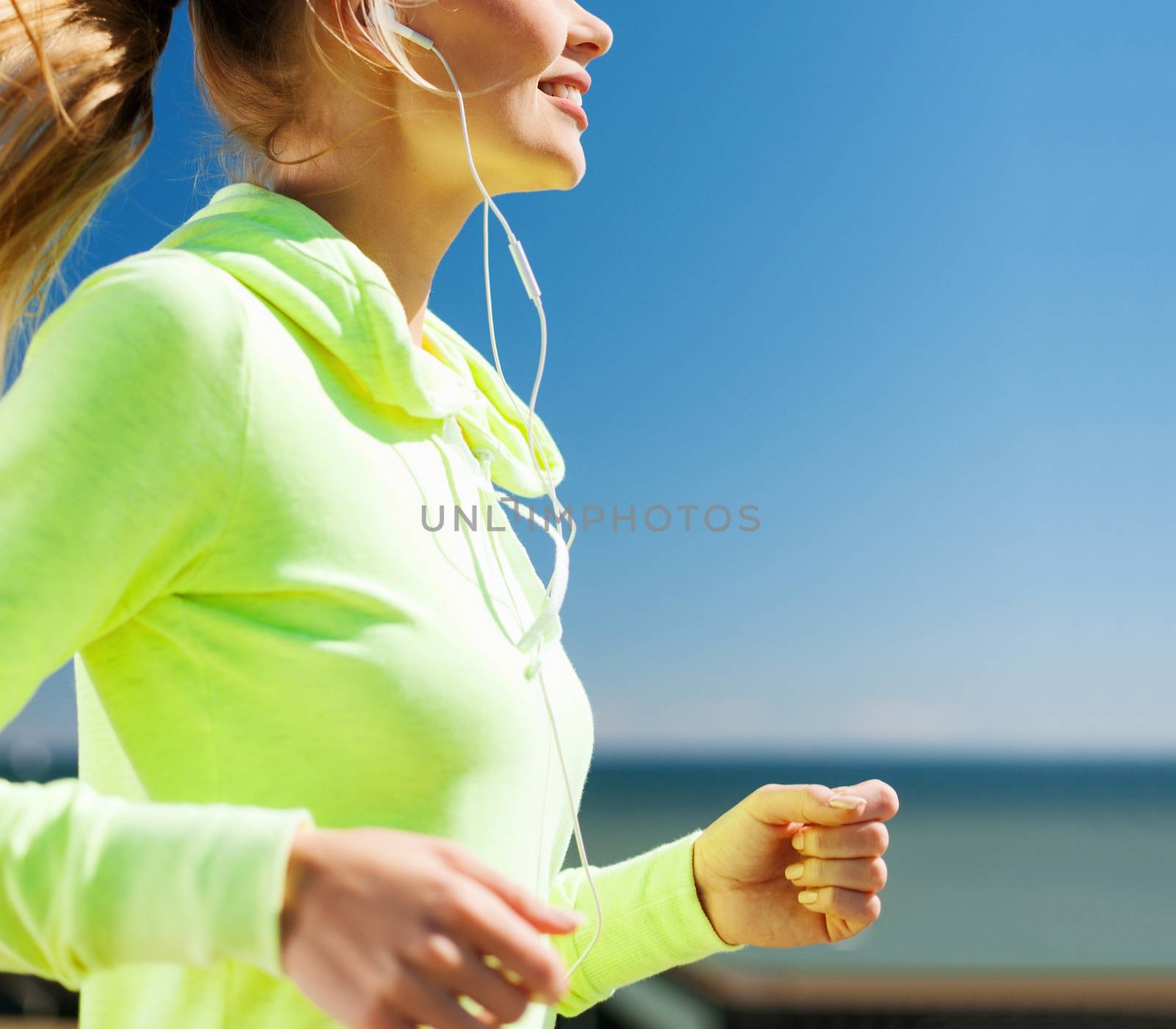 sport and healthy lifestyle concept - woman running and listening music with earphones outdoors