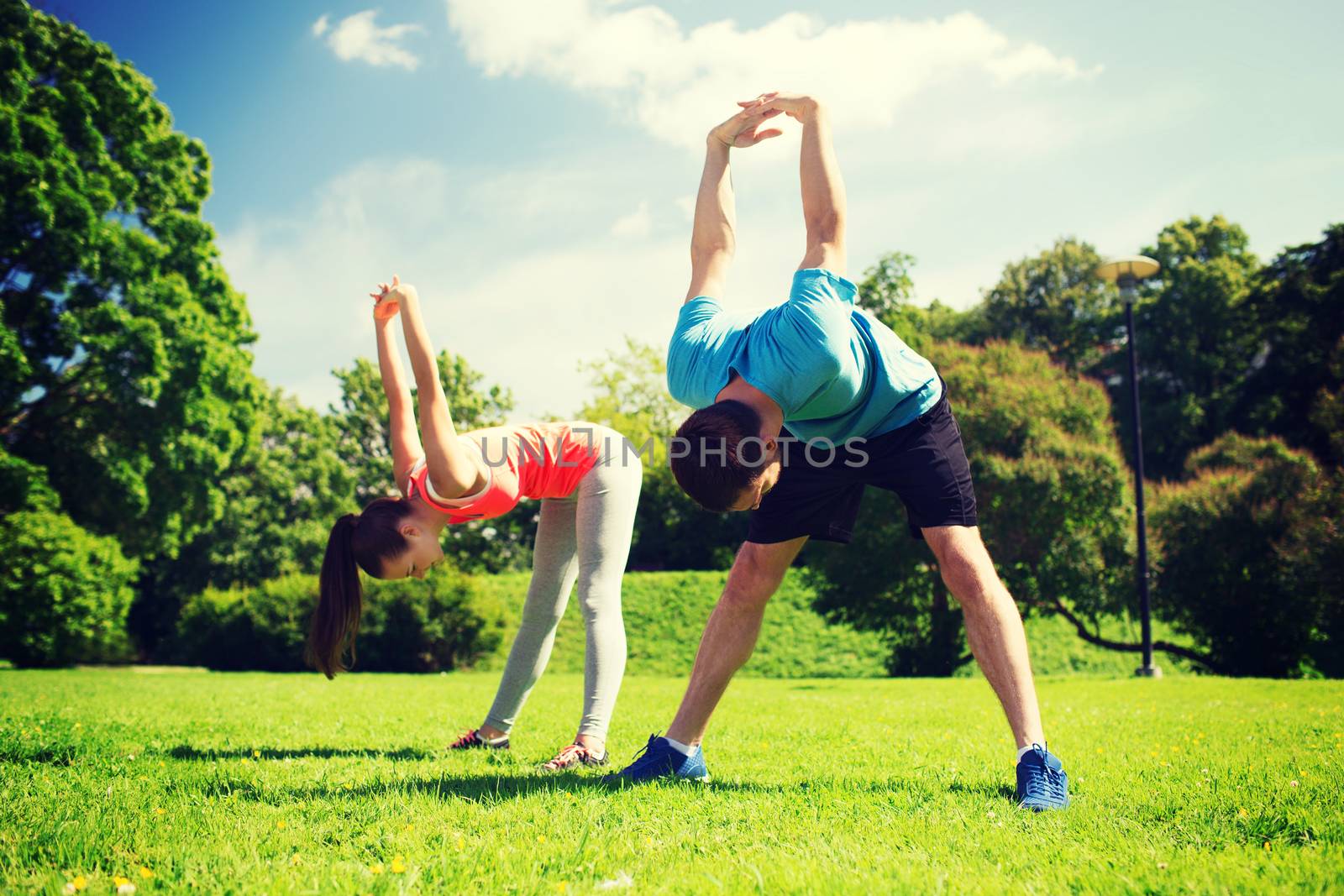 smiling couple stretching outdoors by dolgachov