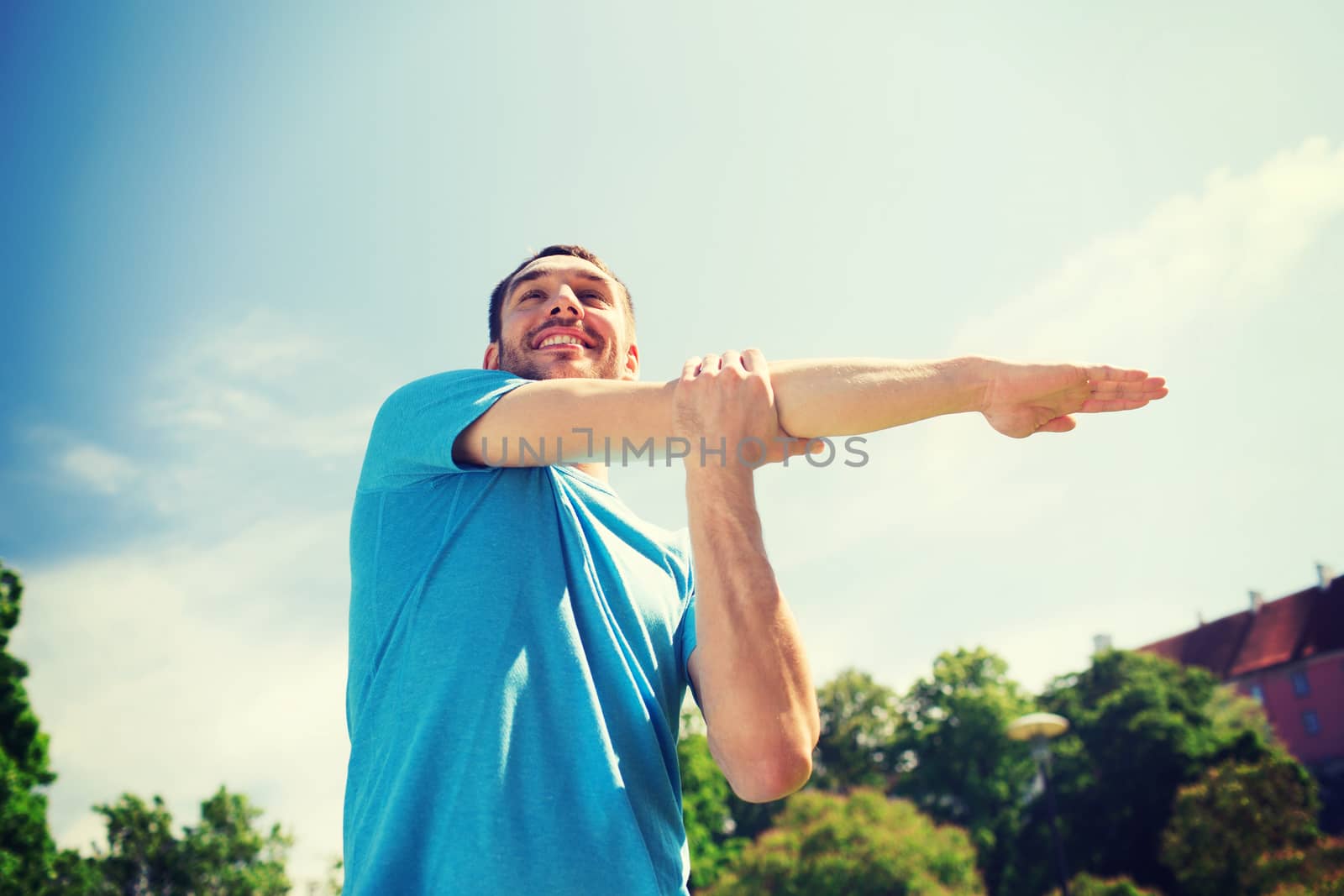 smiling man stretching outdoors by dolgachov